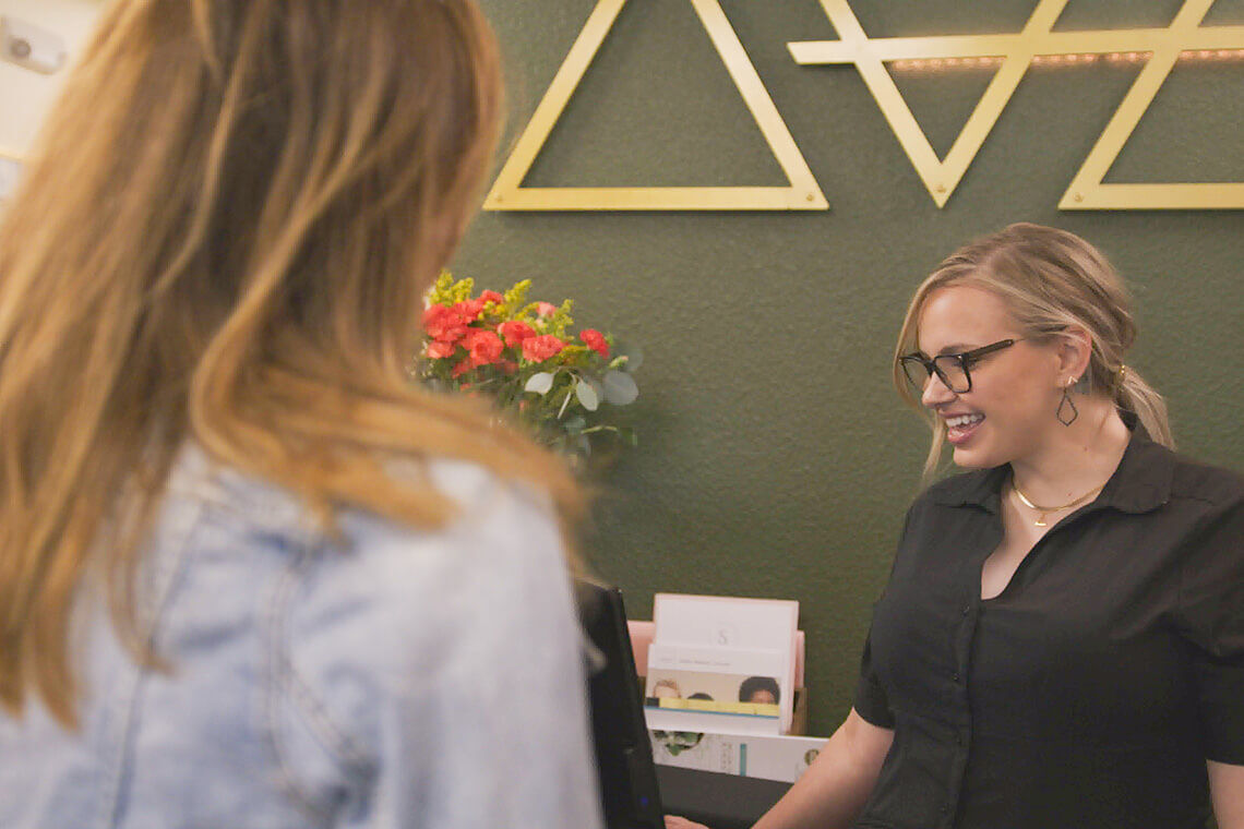 Medspa employee talks with patient at the front desk