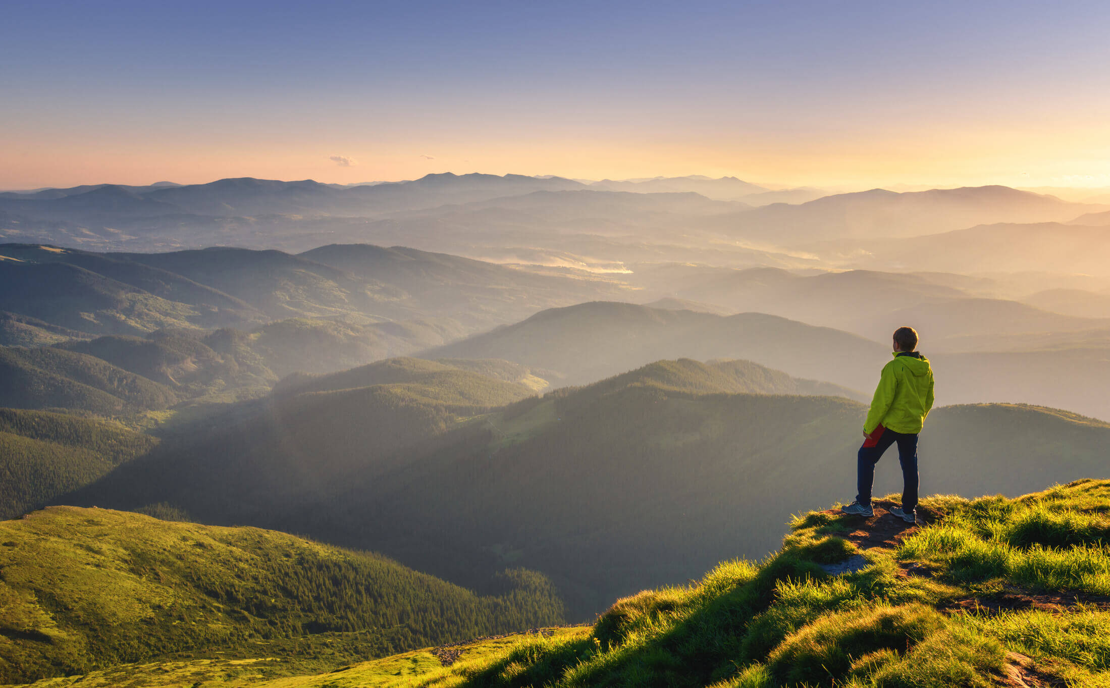 A man standing on a mountaintop watching a sunset